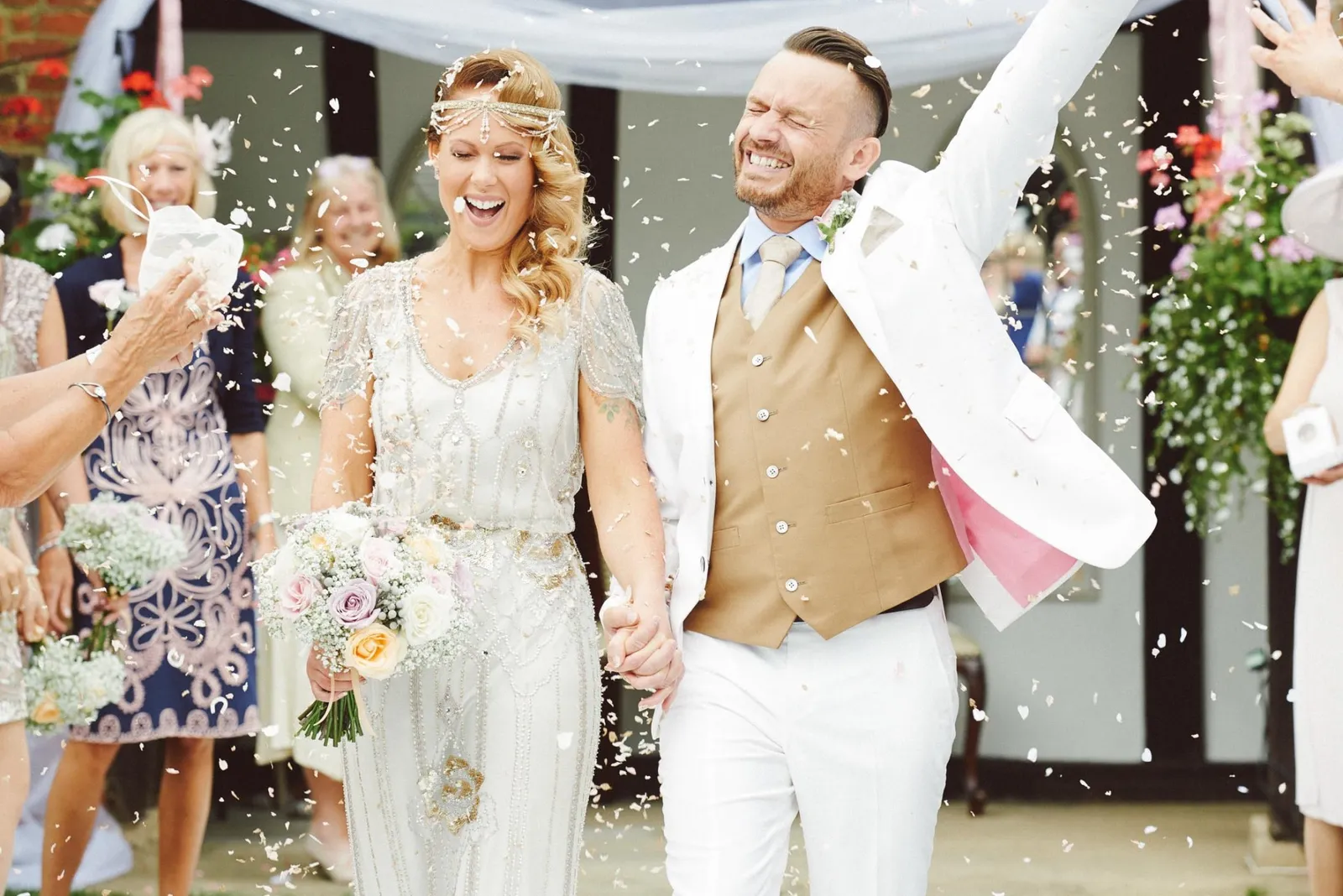 vintage bride and groom celebrating as they walk down outdoor aisle at Woodhall Manor