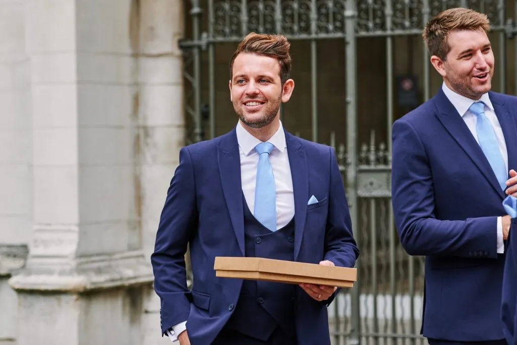 Best man smiling outside of St Margaret's Church in central London 