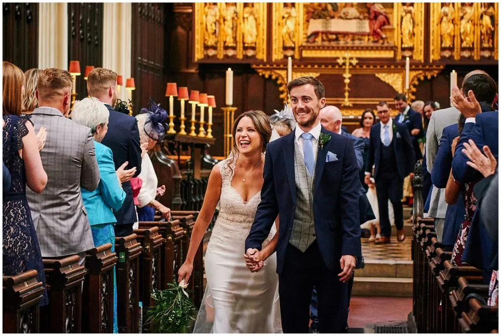 Wedding couple walking down the aisle together in St Margret's Church. 