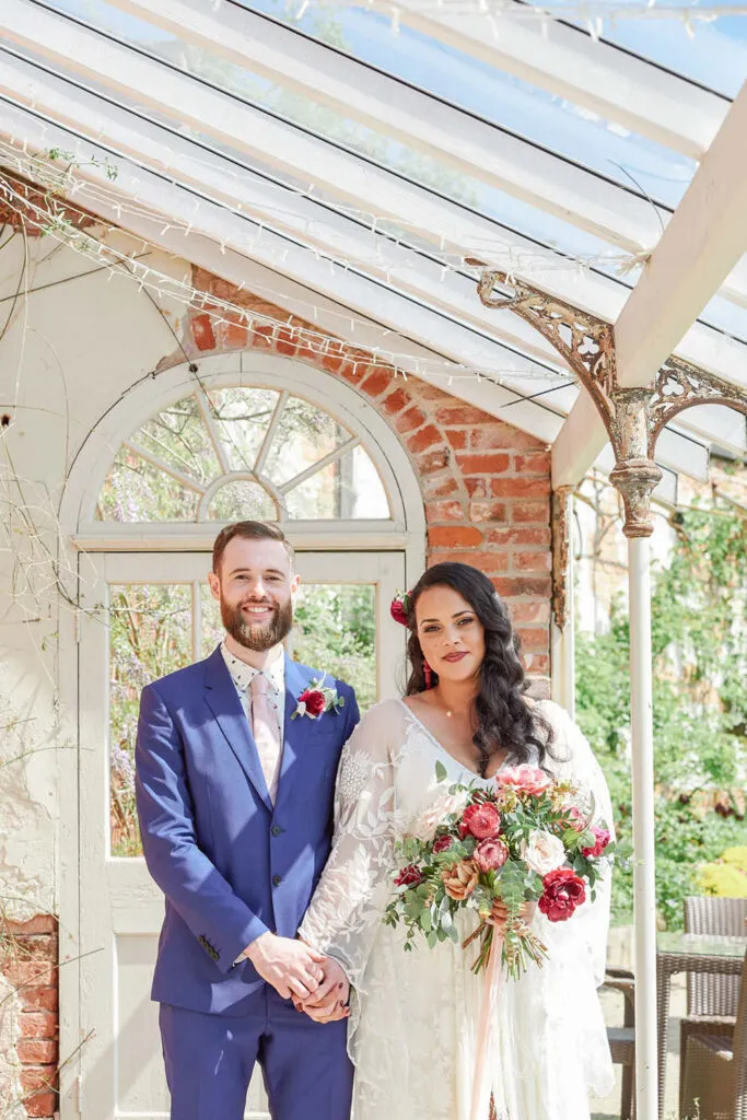 Wedding couple stood under orangery at Pippley Walled Garden wedding venue