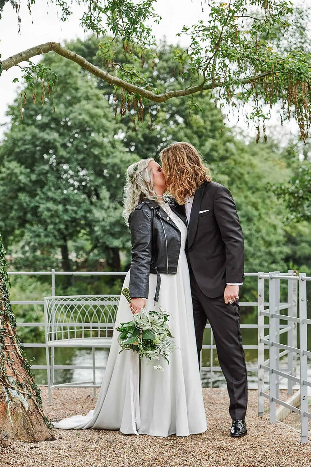 Bride and groom kissing in front of trees at The West Mill in Derby