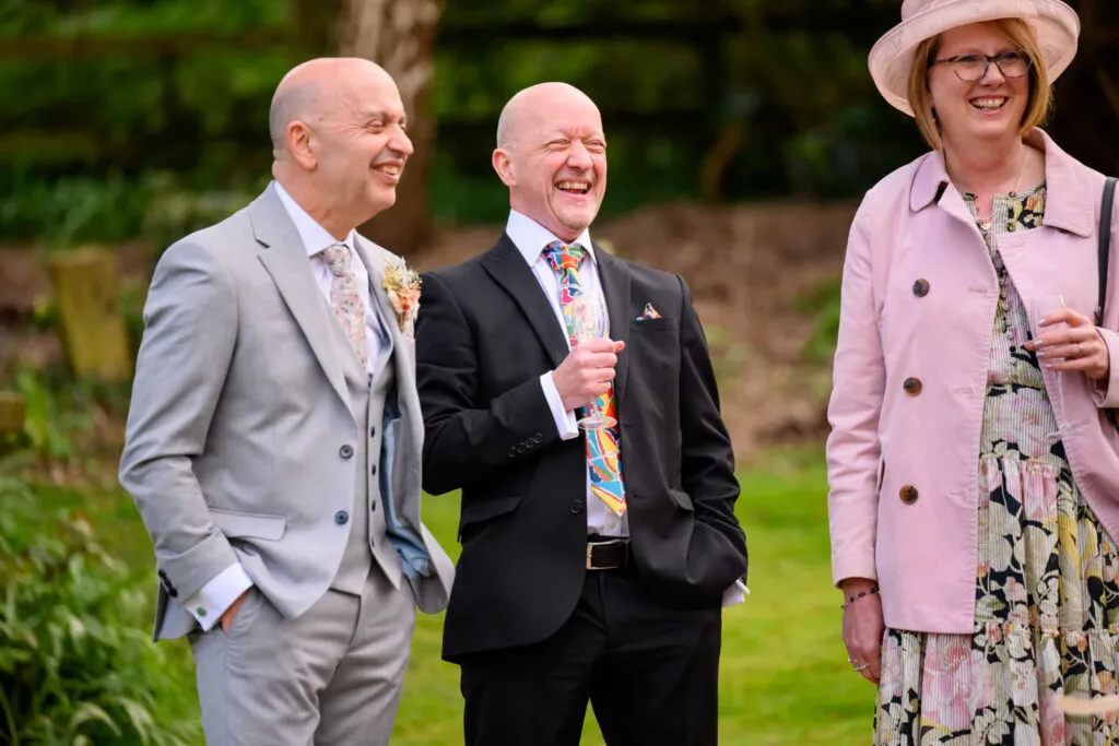 wedding guests chatting and laughing in the gardens at woodborough hall