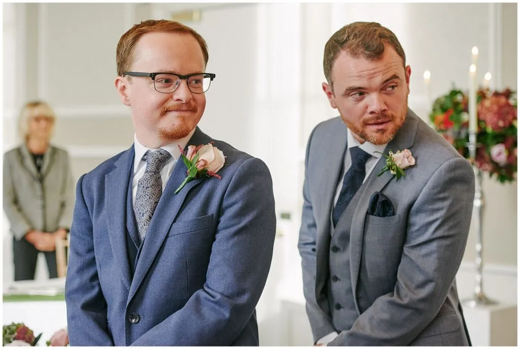 groom and his best man watching bride walk down the isle