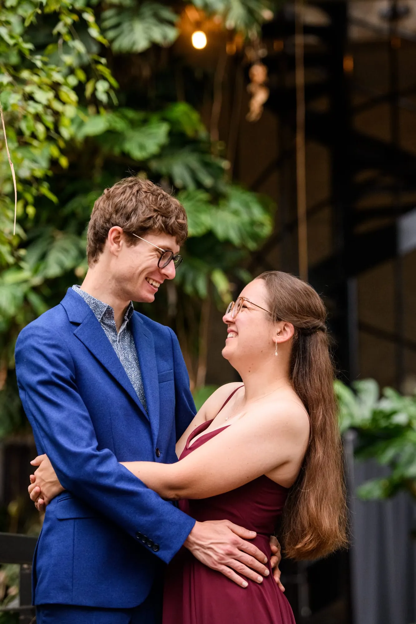 happy wedding couple with arms around each other whilst surrounded by plants