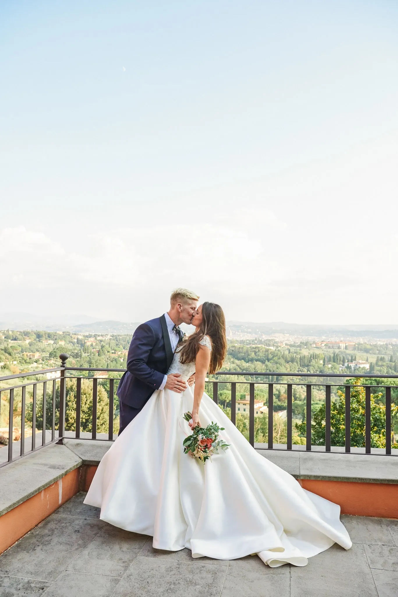 Bride and groom kissing in front of a stunning Tuscany view point