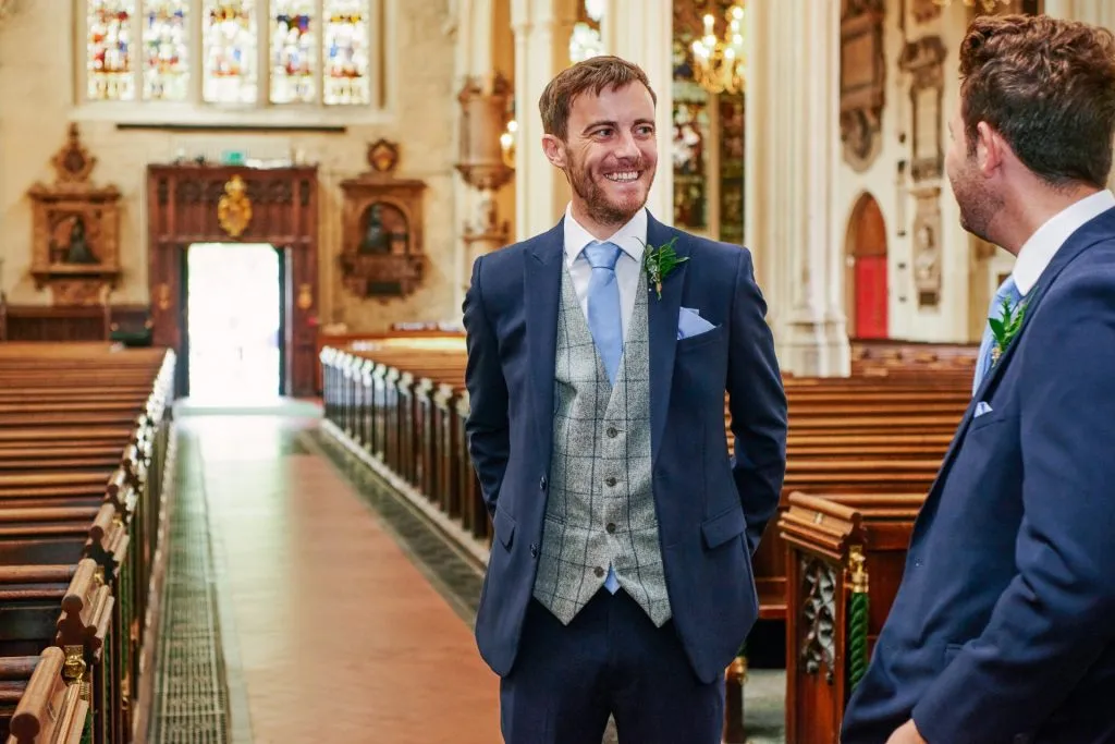 Groom stood smiling inside St Margaret's Church in central London
