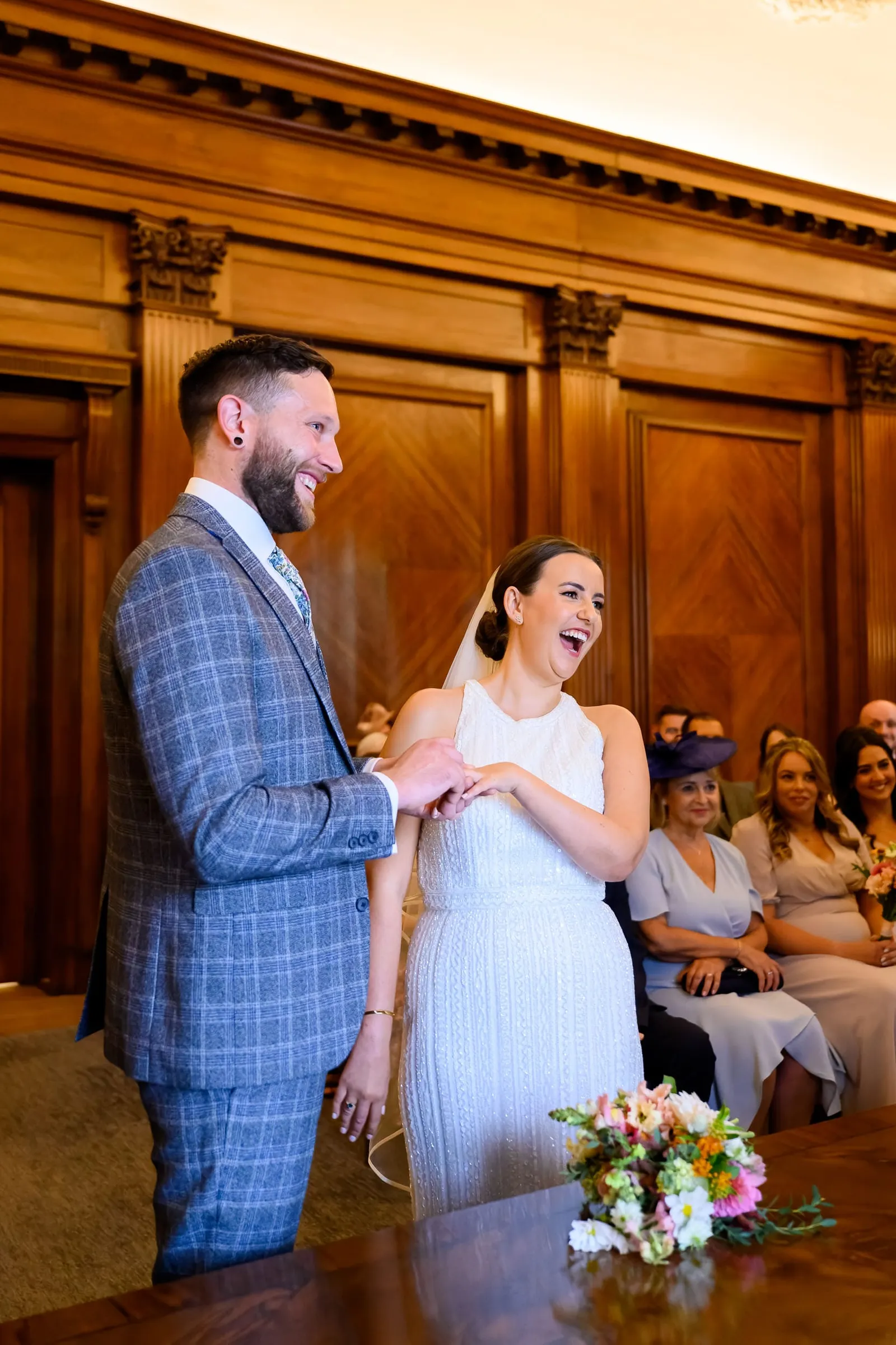 Bride and groom laughing whilst exchanging rings during london ceremony 