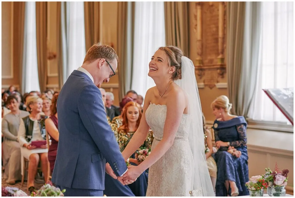 Bride and groom laughing during their fun winter wedding ceremony