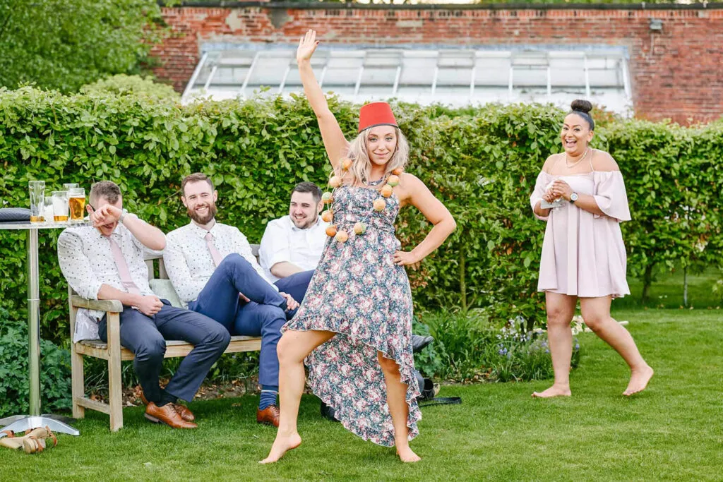 Wedding guest wearing fun red hat and striking a silly pose during outdoor wedding